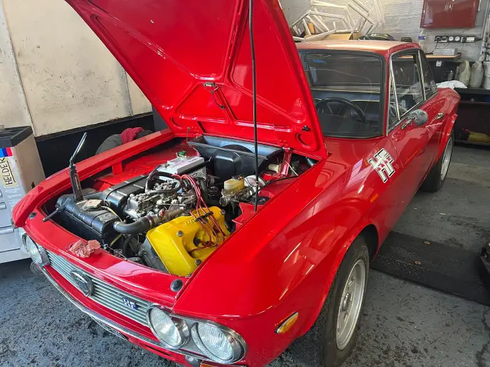 Lancia Fulvia rouge capot ouvert en réparation